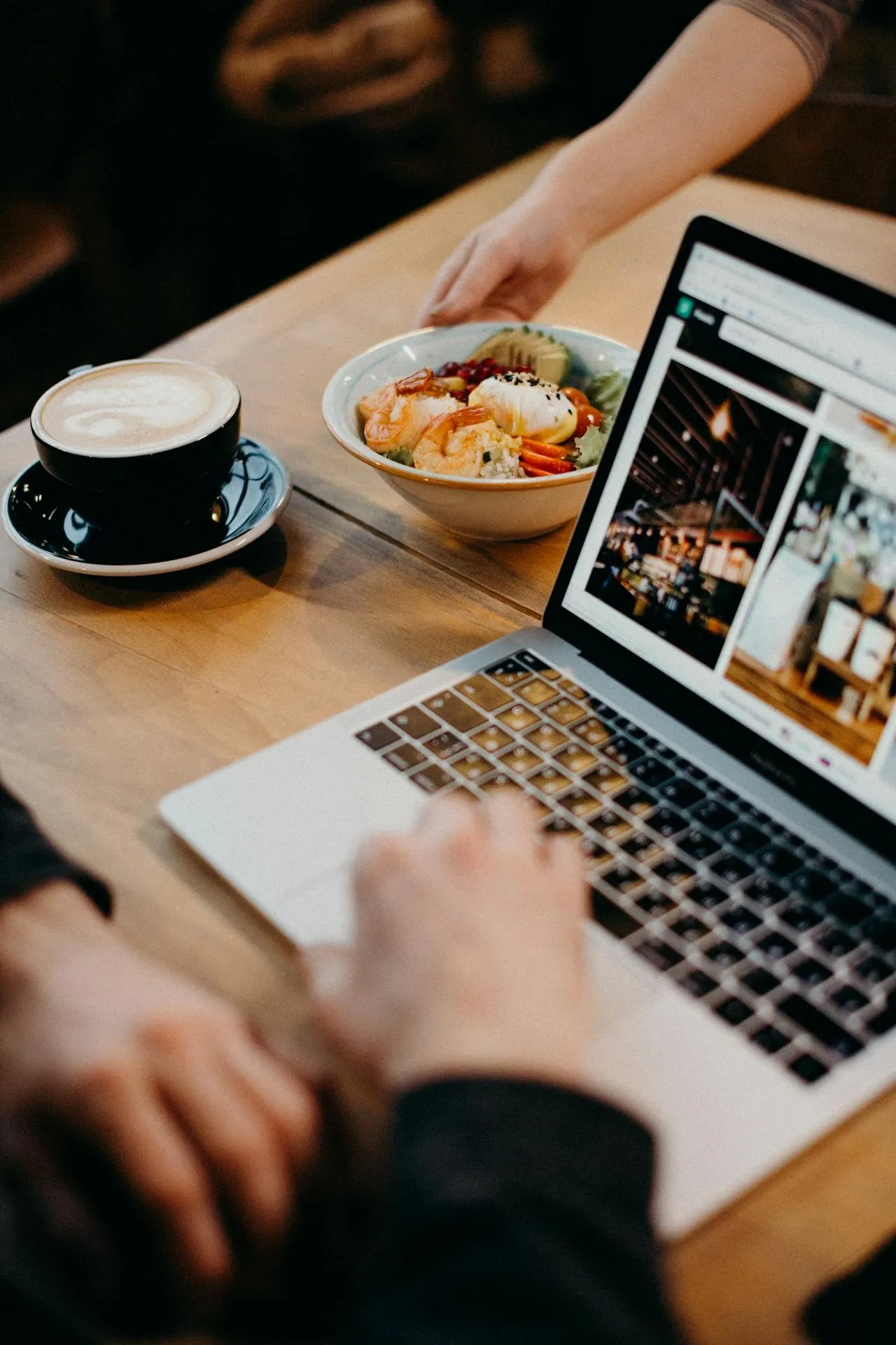 Person working on a laptop with a website open, next to a coffee